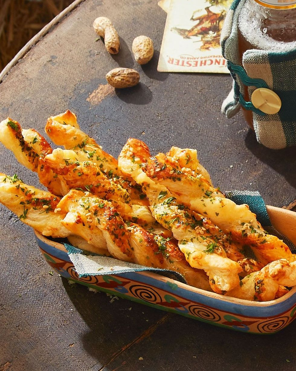 gruyÃ¨re and sesame twists arranged in a serving dish with a tea towel